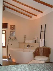 una vasca da bagno bianca in una stanza con sedia di La Suite du Village d'Eze a Èze