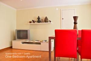 a living room with a table and a tv and red chairs at Akicity Bairro Alto In in Lisbon