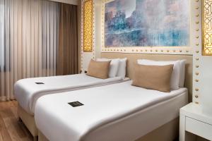two beds in a hotel room with white at Goms Hotel Old City in Istanbul