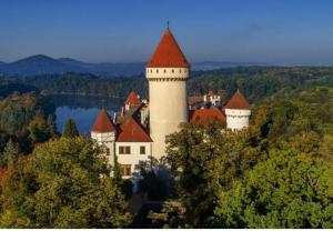 a castle on top of a hill with a body of water at Špulka Hideaway - Romantic Forest Escape near Prague in Teplýšovice