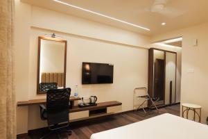 a hotel room with a desk and a tv on the wall at MAG Hotels in Patna
