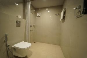 a white bathroom with a shower and a toilet at MAG Hotels in Patna +10 photos