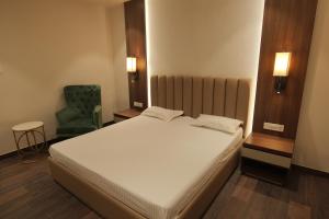 a bedroom with a white bed and a green chair at MAG Hotels in Patna