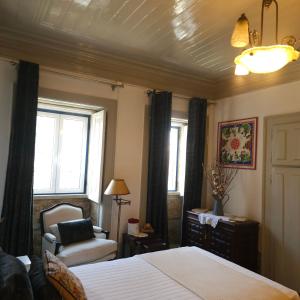 a bedroom with a bed and a chair and windows at O Solarinho Azul in Oledo +16 photos