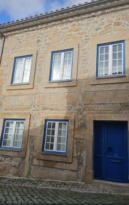 a building with four windows and a blue door at O Solarinho Azul in Oledo