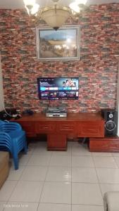 a living room with a television on a brick wall at Villa Raisya Berastagi in Berastagi