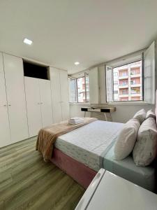 a bedroom with a large bed and two windows at Casa Augusta 6 in Braga