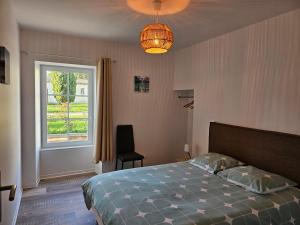 a bedroom with a bed and a window and a chandelier at Les Gîtes de Guillonnet in Anglade