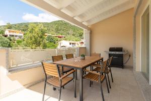 a patio with a wooden table and chairs on a balcony at Borgo Myricae - Giglio in Chia