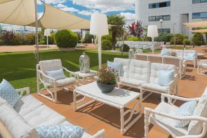 a patio with white furniture and a table and chairs at Elba Madrid Alcalá in Madrid