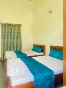 two beds in a room with blue and white at Nhà nghỉ Lena Quan Lạn in Quan Lạn
