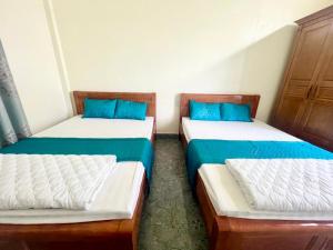two beds in a room with blue pillows at Nhà nghỉ Lena Quan Lạn in Quan Lạn