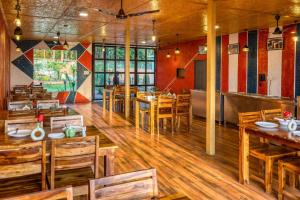 a restaurant with wooden tables and chairs in a room at Earavat Resort in Rāmnagar