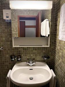 a bathroom with a sink and a mirror and towels at Hotel Fiescherhof in Fiesch