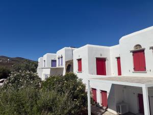 a row of white buildings with red doors at GLAFKY Retreat in Panormos