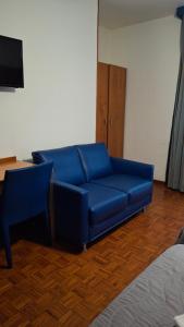 a blue couch in a room with a table and a tv at Locanda El Piron in Chiampo