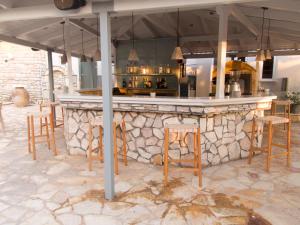 a bar with wooden chairs and a stone counter at Kaiafas Lake Hotel in Kaiafas