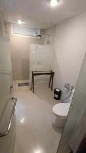 a white bathroom with a toilet and a shower at Dealton Hotel Sanur in Sanur