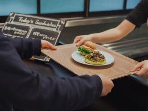 a person holding a table with a plate of food at Hotel Anteroom Kyoto in Kyoto