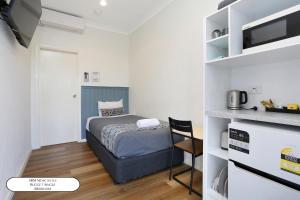 a small bedroom with a bed and a kitchen at Surf Beach Motel Newcastle in Newcastle