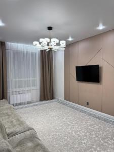 a living room with a couch and a flat screen tv at ЖК Ұлы Дала in Shymkent