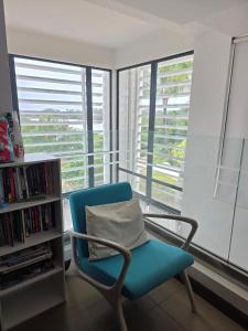 a blue chair sitting in front of a window at Oceanfront in Azuri in Roches Noires