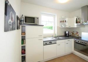 a kitchen with white cabinets and a microwave at Hanne-Hus in Kühlungsborn