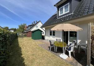 a table and chairs under an umbrella outside of a house at Hanne-Hus in Kühlungsborn