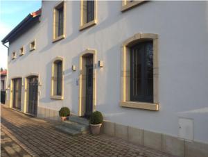 a white building with windows and plants in front of it at Le Pot de Miel d'Ugny in Ugny