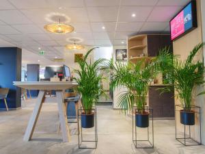 a lobby with potted plants and a table in it at Ibis Laon - Hôtel Restaurant in Laon