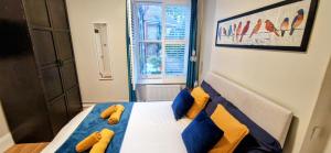 a bedroom with a bed with blue and yellow pillows at Double Bed at Cozy Hailsham in London