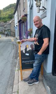 a man standing next to a sign on a street at The Slaters Arms Corris in Machynlleth