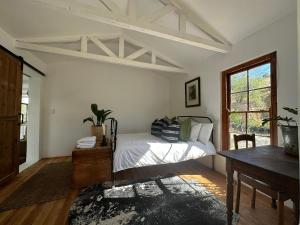 a bedroom with a bed and a table and a window at Cornellskop Country Stay in Botrivier