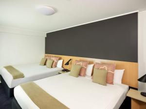 two beds in a hotel room with white and pink pillows at ibis Sydney World Square in Sydney +46 photos