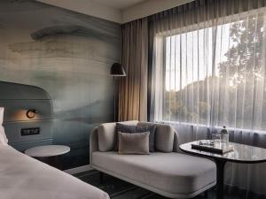 a bedroom with a couch and a table and a window at Novotel Tainui Hamilton in Hamilton +84 photos