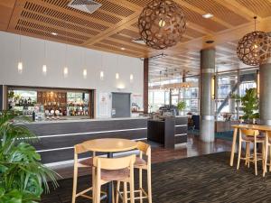 a restaurant with tables and chairs and a bar at Novotel Tainui Hamilton in Hamilton