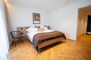 ein Schlafzimmer mit einem Bett und einem Stuhl in der Unterkunft Das Exter - modernes Self Check-in Hotel am Chiemsee in Übersee