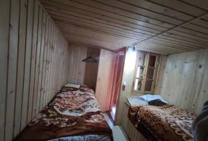 a room with two beds in a wooden room at Hotel Omalo2005 in Omalo