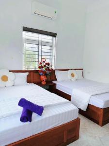 two beds in a room with a purple towel on them at Nhà nghỉ Thảo Thảo Quan Lạn Minh Châu in Quang Ninh