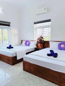 two beds in a room with purple pillows on them at Nhà nghỉ Thảo Thảo Quan Lạn Minh Châu in Quang Ninh