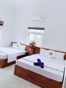 two beds in a room with a purple towel on them at Nhà nghỉ Thảo Thảo Quan Lạn Minh Châu in Quang Ninh