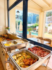 a kitchen with many trays of food on a counter at Helen Hotel in Poros