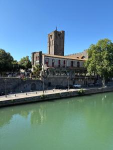 a building next to a river with a building in the background at Grande chambre in Agde