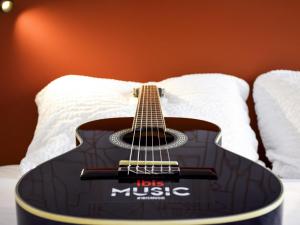 a guitar sitting on top of a bed at ibis Rodez Centre in Rodez +71 photos
