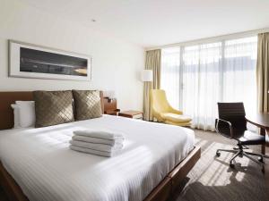 a hotel room with a bed with towels on it at Novotel Canberra in Canberra