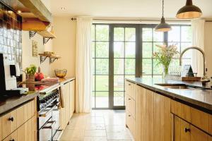 a kitchen with wooden cabinets and a large window at Muntershof in Zottegem +15 photos