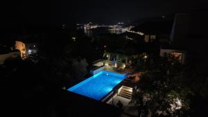 a swimming pool at night with a city in the background at Villa Verra in Pržno