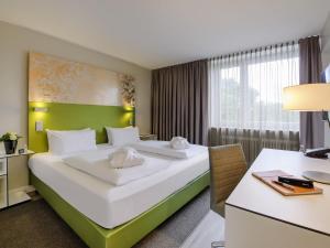 a hotel room with two beds and a desk at Congress Hotel Mercure Nürnberg an der Messe in Nuremberg +108 photos