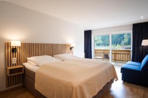 a bedroom with a large bed and a blue chair at Hotel Loenfjord Loen in Loen