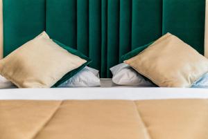 a bed with two pillows and a green wall at GreenRoom Kunigiškės in Palanga